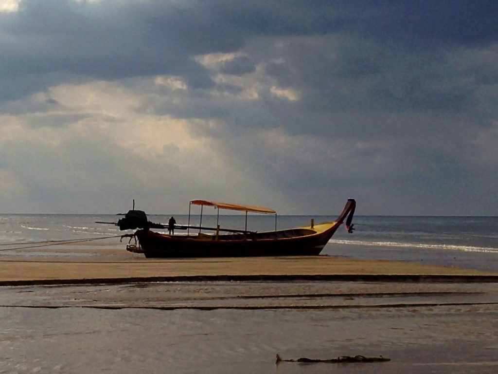 Longtail boat sits on the sand of a beautiful beach in Thailand